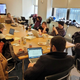 A group of people sit around a table in a conference room.